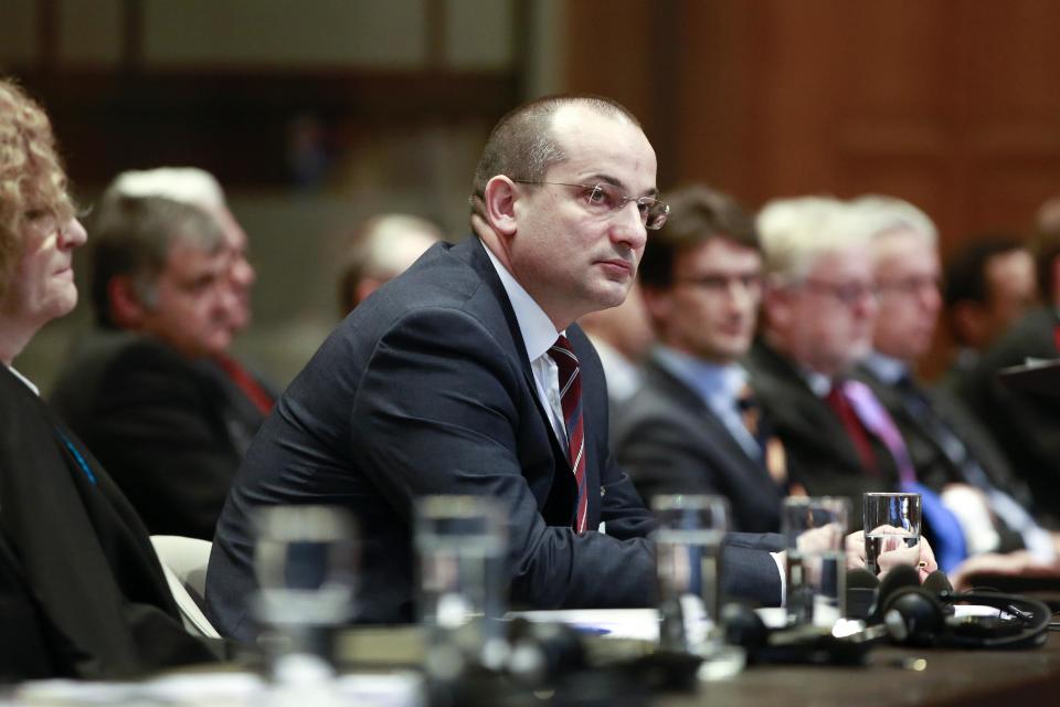 Croatian Minister Orsat Miljenic, center, awaits the start of public hearings at the International Court of Justice (ICJ) in The Hague, Netherlands, Monday, March 3, 2014. Croatia is accusing Serbia of genocide during fighting in the early 1990's as the former Yugoslavia shattered in spasms of ethnic violence, in a case at the United Nations' highest court that highlights lingering animosity in the region. Croatia is asking the ICJ to declare that Serbia breached the 1948 Genocide Convention when forces from the former Federal Republic of Yugoslavia attempted to drive Croats out of large swaths of the country after Zagreb declared independence in 1991. (AP Photo/Jiri Buller)