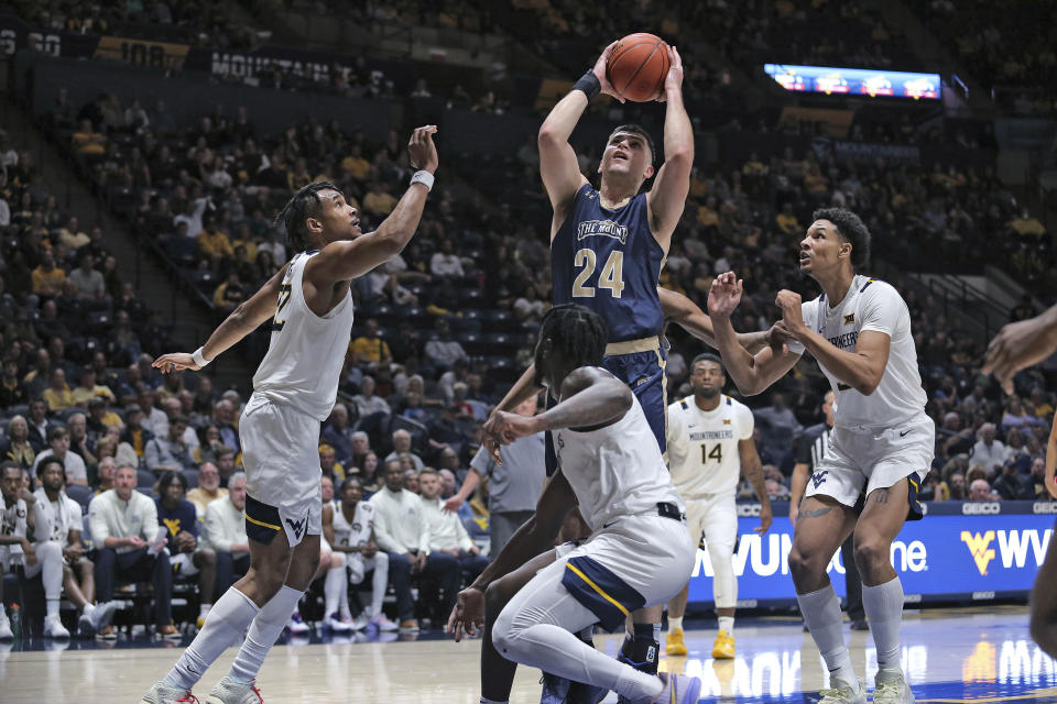Mount St. Mary's forward Frantisek Barton (24) shoots over West Virginia forward Josiah Harris, left, guard Joe Toussaint, front, and forward Tre Mitchell, right, during the first half of an NCAA college basketball game in Morgantown, W.Va., Monday, Nov. 7, 2022. (AP Photo/Kathleen Batten)