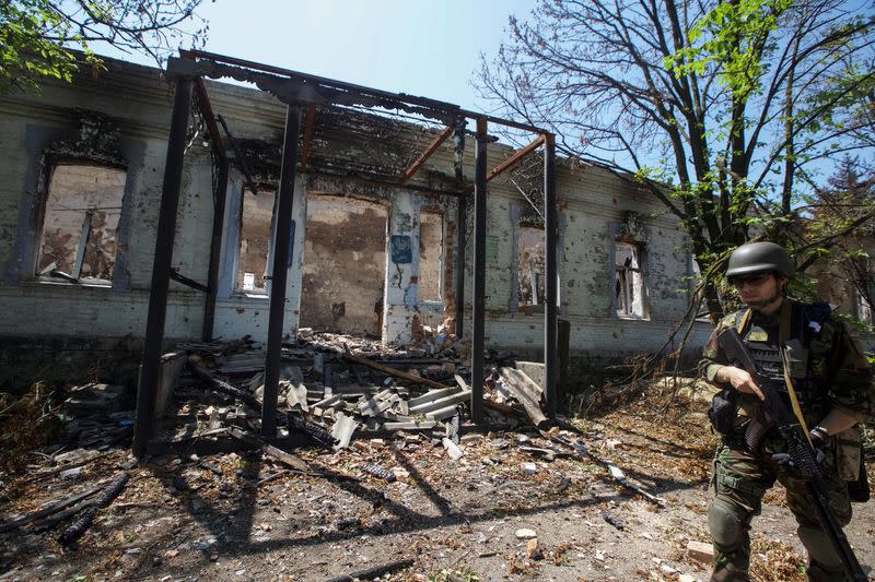 A police officer checks an area during an evacuation of local residents between shelling in the village of Novomykhailivka