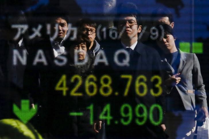 People are reflected in a display showing market indices outside a brokerage in Tokyo, Japan, February 10, 2016. REUTERS/Thomas Peter