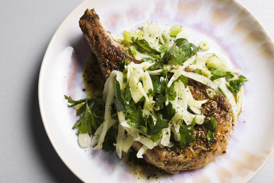 This image released by Milk Street shows a recipe for seared pork chops with a fennel and herb salad. (Milk Street via AP)