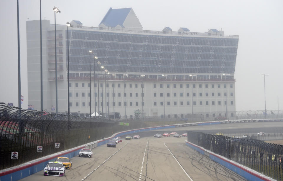 Jimmie Johnson leads the field with visible mist in the air.