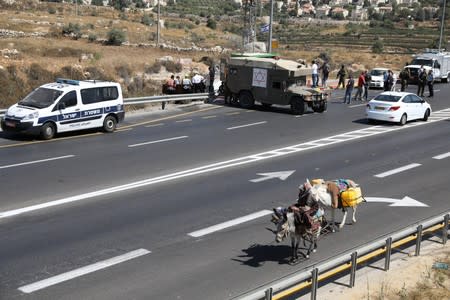 Woman rides a donkey as she passes the scene of what Israeli military said is a car-ramming attack near the settlement of Elazar in the Israeli-occupied West Bank