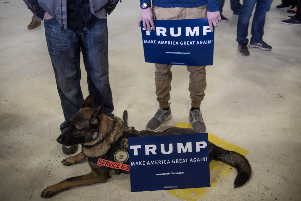 Attendees hold signs while standing by a service dog during a campaign rally for Donald Trump at the Port Columbus International Airport in Columbus, Ohio, on March 1, 2016.