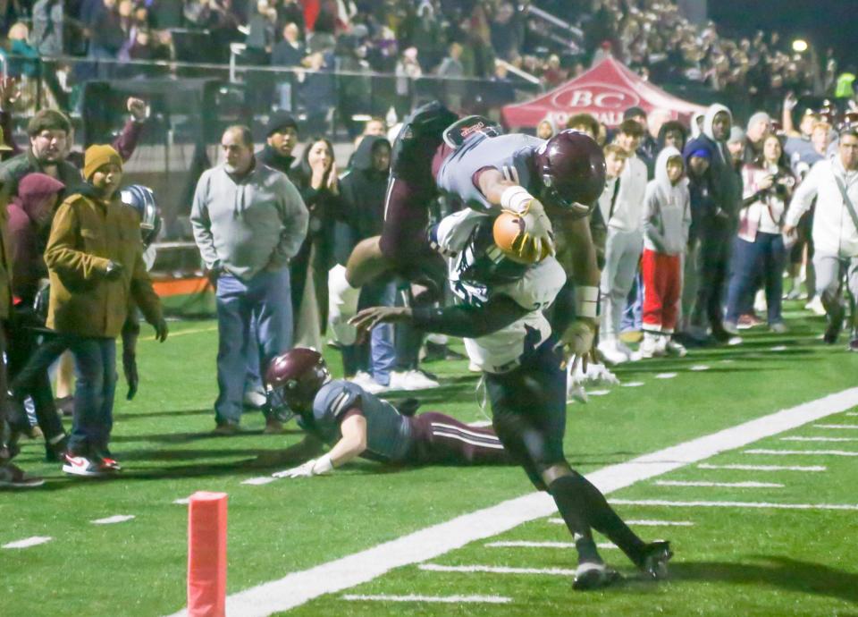 Benedictine's Za'Quan Bryan stretches the ball out over the goal line as he goes airborne over Spalding kicker Salomon Trazie to cap off a 59-yard punt return with a touchdown during last Friday night's state playoff game at Memorial Stadium.