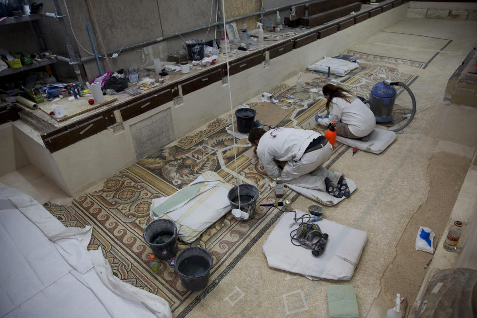 FILE - In this Thursday, Dec. 6, 2018 photo, restoration experts work on a mosaic inside the Church of the Nativity, built atop the site where Christians believe Jesus Christ was born, in the West Bank City of Bethlehem. The U.N. cultural agency says Bethlehem's Church of the Nativity is no longer considered endangered world heritage, thanks to extensive restoration work on the traditional birthplace of Jesus. (AP Photo/Majdi Mohammed)