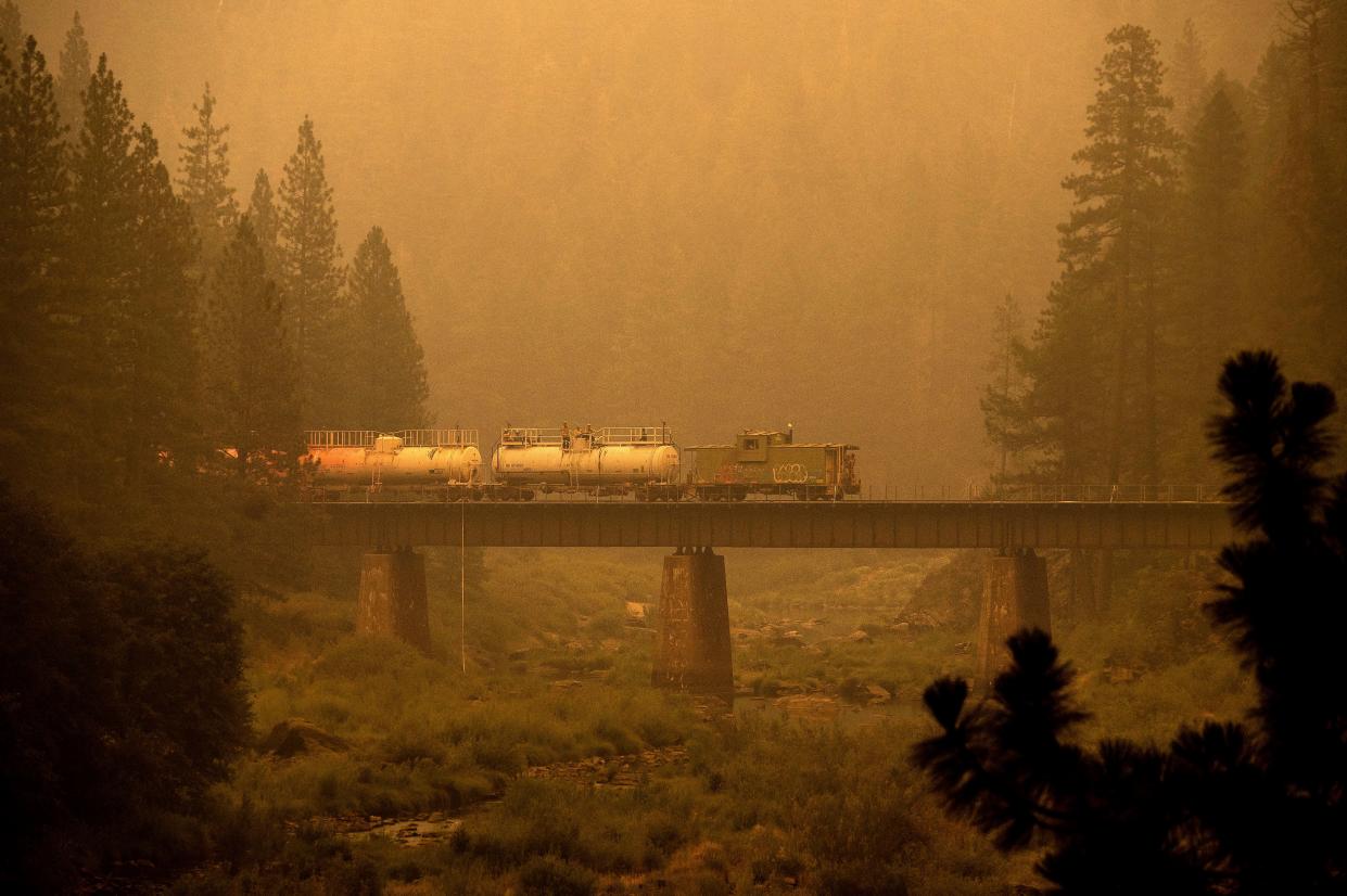 A fire train crosses a bridge as the Dixie Fire burns in Plumas County, Calif. on Saturday, July 24, 2021. The train is capable of spraying retardant to coat tracks and surrounding land.