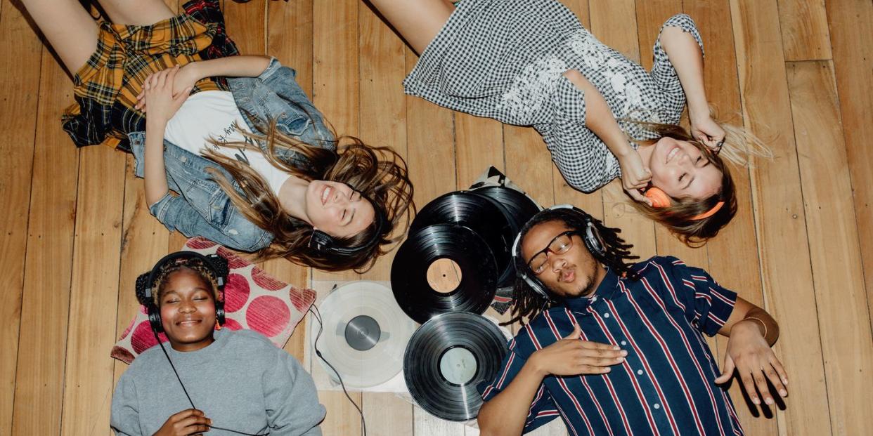 group of young friends listening to music with vinyls scattered about