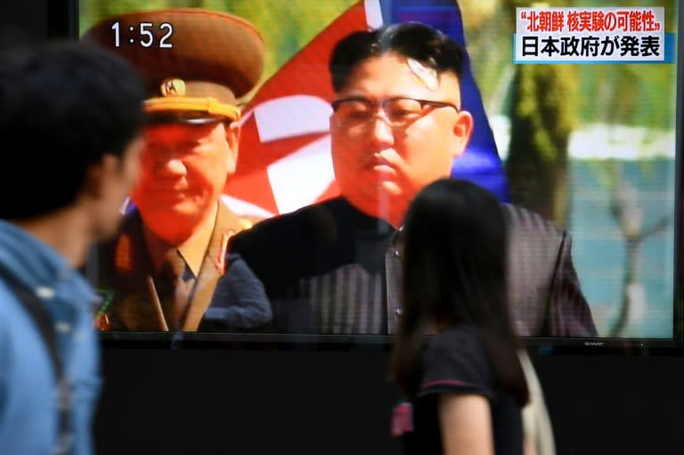 People walk past a TV in Tokyo broadcasting news about the North Korean nuclear test on September 3, 2017