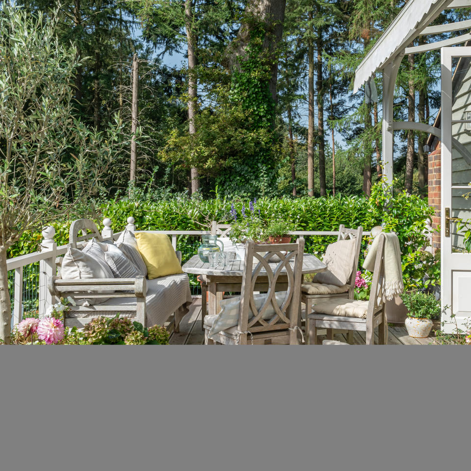 Outdoor dining area on a veranda surrounded by forest