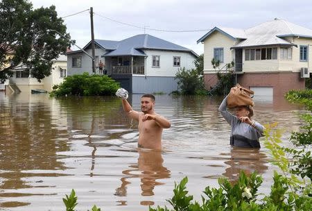 Local residents wade through floodwaters near their homes in the northern New South Wales town of Lismore, Australia, March 31, 2017 after heavy rains associated with Cyclone Debbie swelled rivers to record heights across the region. AAP/Dave Hunt/via REUTERS