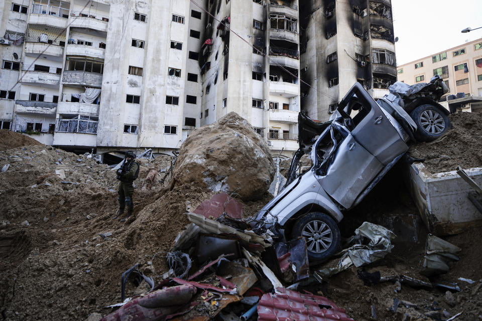 An Israeli soldier takes up a position next to a damaged car that is piled up with concrete as protection for Israeli soldiers next to UNRWA headquarters where the military discovered tunnels underneath the U.N. agency that the military says Hamas militants used to attack its forces during a ground operation in Gaza, Thursday, Feb. 8, 2024. The Israeli military says it has discovered tunnels underneath the main headquarters of the U.N. agency for Palestinian refugees in Gaza City, alleging that Hamas militants used the space as an electrical supply room. The unveiling of the tunnels marked the latest chapter in Israel's campaign against the embattled agency, which it accuses of collaborating with Hamas. (AP Photo/Ariel Schalit)