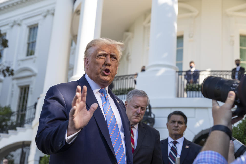 Donald Trump stands near the White House before someone holding a camera. Mark Meadows is seen just over his shoulder.