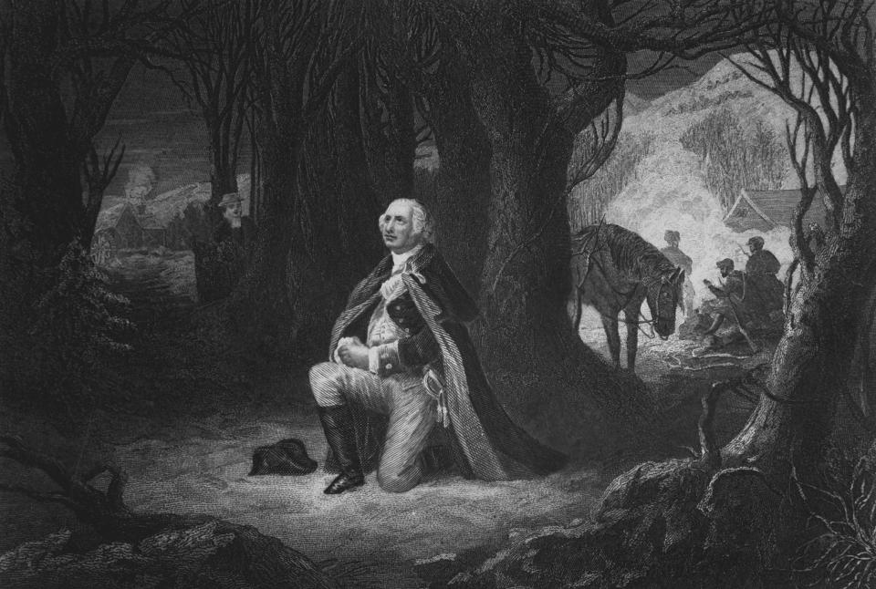 Engraving depicting General George Washington kneeling in prayer, while his soldiers camp in the background, at Valley Forge, Pennsylvania, during the winter of 1777. Copy of engraving by John McRae after a painting by Henry Brueckner, published 1866. | Interim Archives/Getty Images