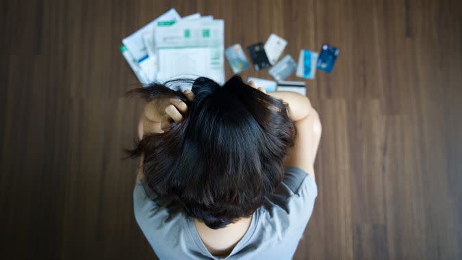 Woman with credit cards and bills spread on the floor