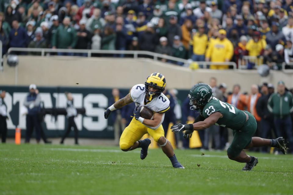 Michigan running back Blake Corum (2) runs against Michigan State safety Darius Snow (23) during the second half at Spartan Stadium in East Lansing on Saturday, Oct. 30, 2021. 