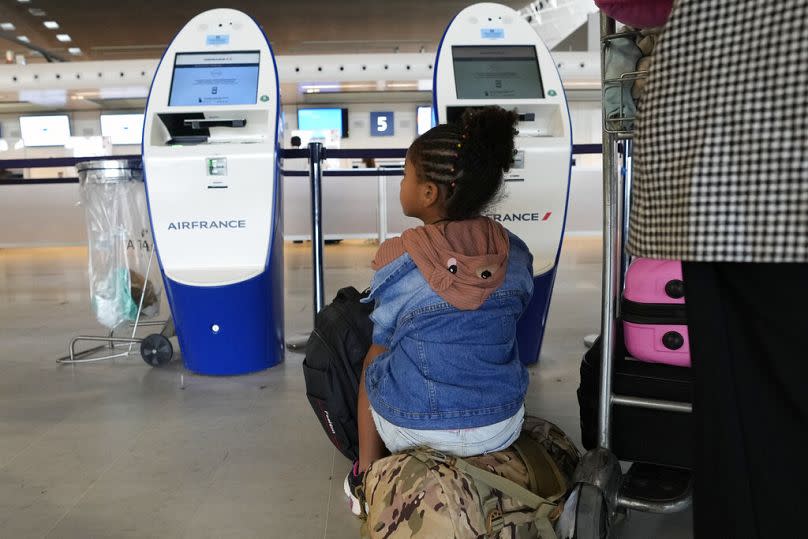 Travelers wait by empty check-in desks at Roissy Charles de Gaulle airport, north of Paris.