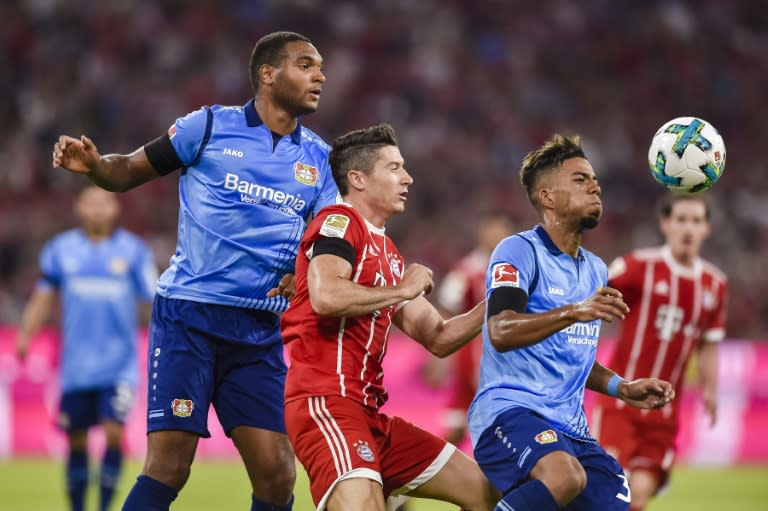 Bayern Munich's striker Robert Lewandowski (C) and Leverkusen's defender Benjamin Henrichs (R) vie for the ball during the German First division Bundesliga football match August 18, 2017