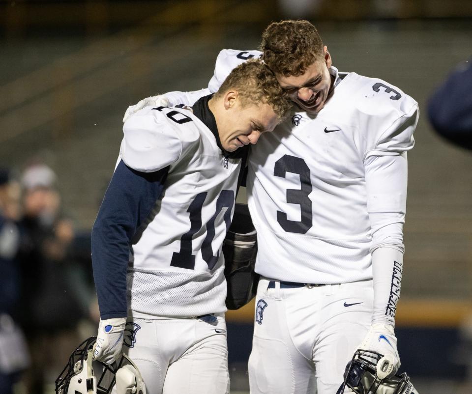 McDowell's Hunter Hodges (3) and Joey Orlando (3) embrace after a PIAA Class 6A quarterfinal football game on Friday at Mt. Lebanon High School in Pittsburgh. The Trojans lost to the Blue Devils 47-14.