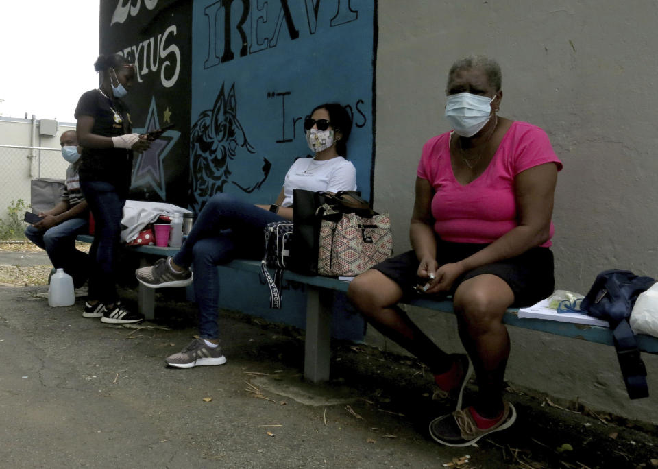 Electoral officials wait for ballots to arrive at a voting center in Carolina, Puerto Rico, Sunday, Aug. 9, 2020. Puerto Rico's primaries were marred by a lack of ballots in a majority of centers across the U.S. territory, forcing frustrated voters who braved a spike in COVID-19 cases to turn around and go back home. (AP Photo/Danica Coto)