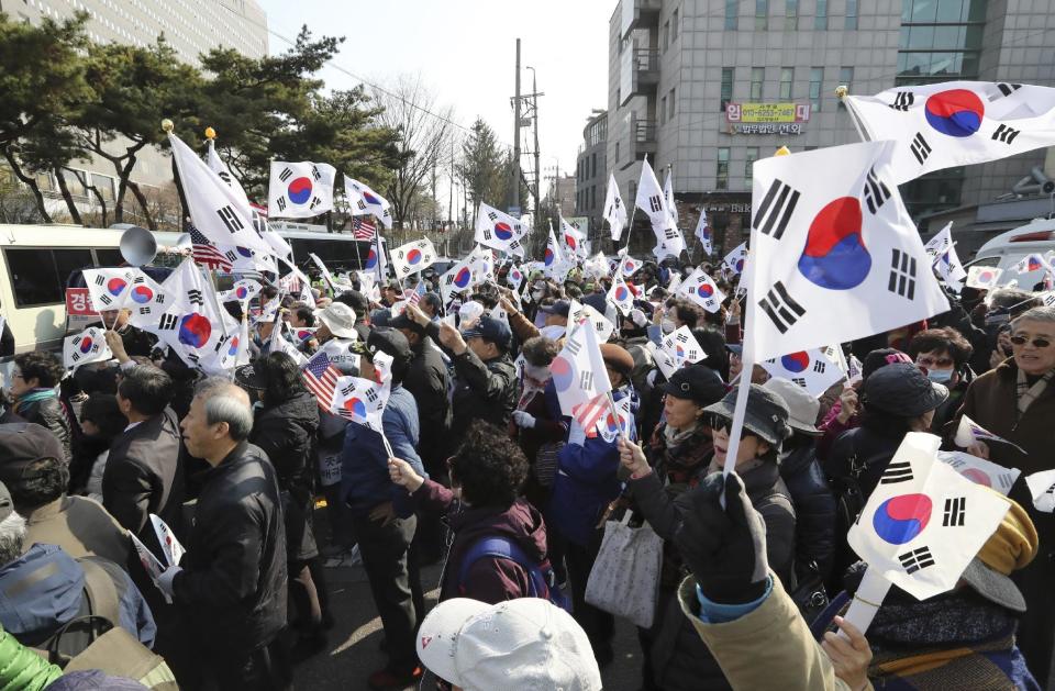 Supporters of South Korean ousted President Park Geun-hye wave flags outside of a prosecutors' office in Seoul, South Korea, Tuesday, March 21, 2017. Park said she was "sorry" to the people as she arrived Tuesday at a prosecutors' office for questioning over a corruption scandal that led to her removal from office. (AP Photo/Lee Jin-man)