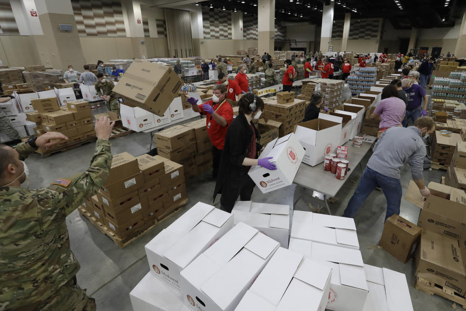 Volunteers from Midwest Food Bank and The Salvation Army worked with Lucas Oil Stadium staff and Indiana National Guard members to box food items that will be sent to Indiana families, Friday, April 17, 2020, in Indianapolis. The food boxes were with shelf-stable items designed to help supplement the pantries of families who are struggling due to COVID-19 shut-downs. The Salvation Army prepped 10,000 boxes of food to help Hoosier families in need. (AP Photo/Darron Cummings)