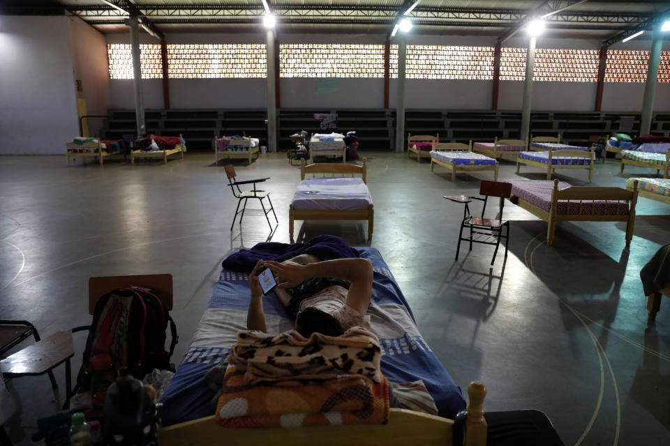 A youth rests on a bed with his cellphone at school turned into a government-run shelter where citizens returning home are required by law to quarantine for two weeks and pass two consecutive COVID-19 tests, as a preventive measure amid the COVID-19 pandemic in Ciudad del Este, Paraguay, Thursday, June 24, 2020. The youth said he was quarantined for 70 total days before he left. As nearby nations grapple with uncontrolled spread of the novel coronavirus, the small, poor, landlocked nation of Paraguay appears to be controlling the disease, with just a few thousand confirmed cases and a few dozen deaths. (AP Photo/Jorge Saenz)