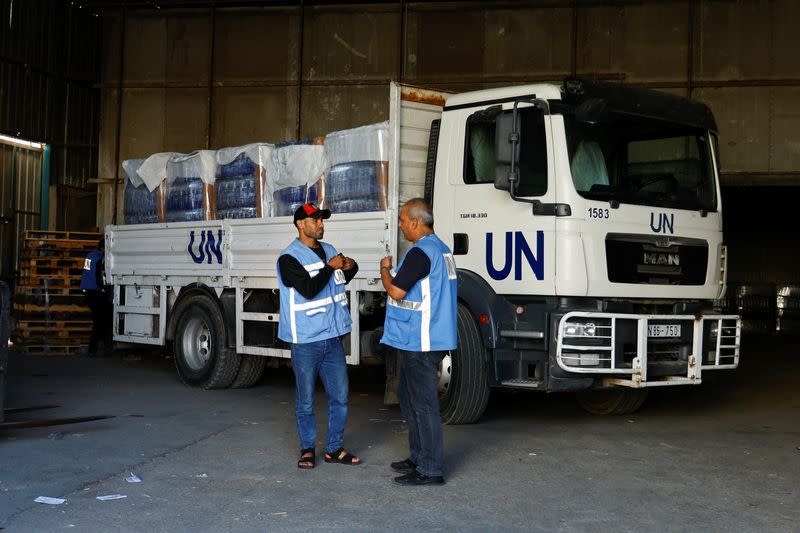 FOTO DE ARCHIVO. Trabajadores junto a un vehículo de las Naciones Unidas, mientras clasifican la ayuda que se distribuirá a los palestinos, mientras continúa el conflicto entre Israel y el grupo islamista palestino Hamás, en una instalación gestionada por las Naciones Unidas, en Jan Yunis, en el sur de la Franja de Gaza