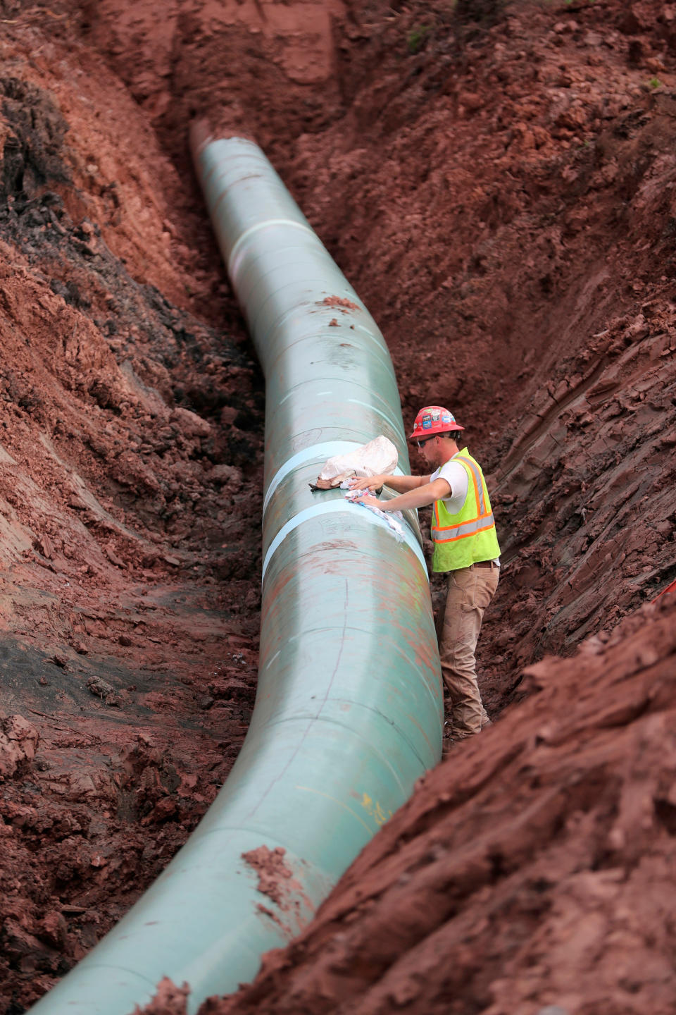 FILE - In this Aug. 21, 2017, file photo, a pipe fitter lays the finishing touches to the replacement of Enbridge Energy's Line 3 crude oil pipeline stretch in Superior, Wisc. After President Joe Biden revoked Keystone XL's presidential permit and shut down construction of the long-disputed pipeline that was to carry oil from Canada to Texas, opponents of other pipelines hoped the projects they've been fighting would be next.(Richard Tsong-Taatarii /Star Tribune via AP)