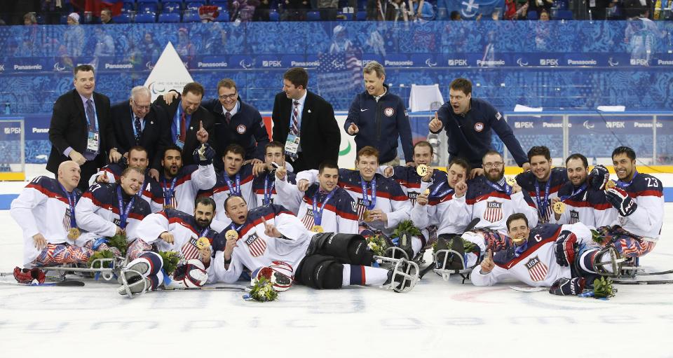 United States players and team officials pose for a team photo after they won gold medals at ice sledge hockey match between United States and Russia at the 2014 Winter Paralympics in Sochi, Russia, Saturday, March 15, 2014. United States won 1-0. (AP Photo/Pavel Golovkin)