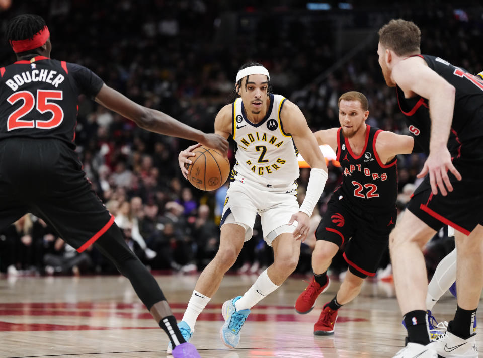 Indiana Pacers guard Andrew Nembhard (2) drives between Toronto Raptors forward Chris Boucher (25), guard Malachi Flynn (22) and centre Jakob Poeltl (19) during the second half of an NBA basketball game in Toronto, Wednesday, March 22, 2023. (Frank Gunn/The Canadian Press via AP)