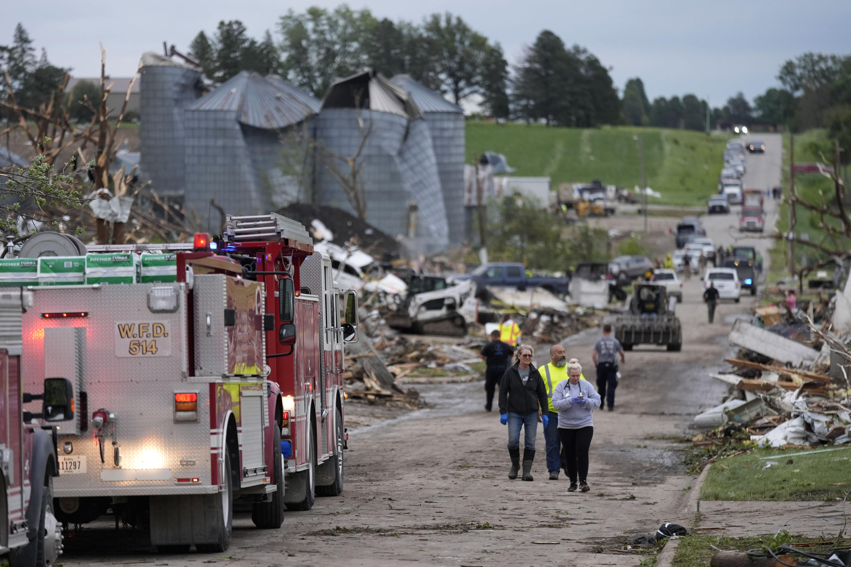 People walk down a street past damage after a tornado on Tuesday in Greenfield, Iowa.