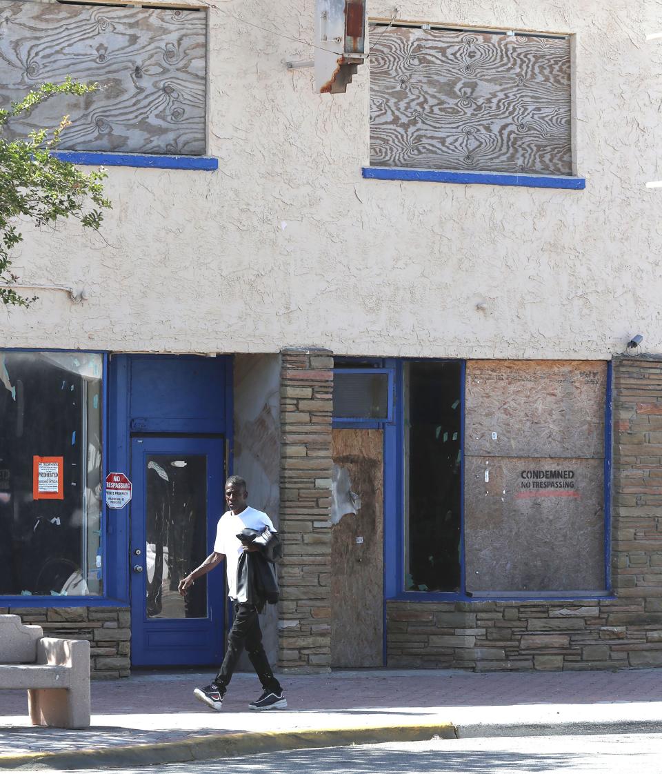 A man walks past a boarded up business, Monday April 29,2024 in the 500 block of Mary McLeod Bethune Blvd..