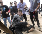 A supporter of President Donald Trump, center, clashes with an anti-Trump protester, bottom center, in Huntington Beach, Calif., on Saturday, March 25, 2017. Violence erupted when a march of about 2,000 Trump supporters at Bolsa Chica State Beach reached a group of about 30 counter-protesters, some of whom began spraying pepper spray, said Capt. Kevin Pearsall of the California State Parks Police. (Mindy Schauer/The Orange County Register via AP)