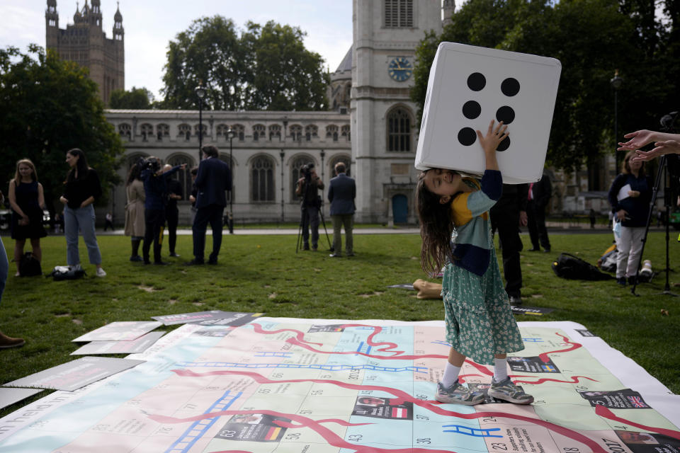 Gabriella, the seven year old daughter of imprisoned British-Iranian Nazanin Zaghari-Ratcliffe, joins in a game on a giant snakes and ladders board in Parliament Square, London, to show the "ups and downs" of Zaghari-Ratcliffe's case to mark the 2,000 days she has been detained in Iran, Thursday, Sept. 23, 2021. Zaghari-Ratcliffe was originally sentenced to five years in prison after being convicted of plotting the overthrow of Iran's government, a charge that she, her supporters and rights groups deny. While employed at the Thomson Reuters Foundation, the charitable arm of the news agency, she was taken into custody at the Tehran airport in April 2016 as she was returning home to Britain after visiting family. (AP Photo/Matt Dunham)