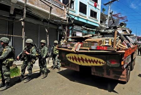 FILE PHOTO: An Armoured Personnel Carrier (APC) and government troops march towards Mapandi bridge after 100 days of intense fighting between soldiers and insurgents from the Maute group, who have taken over parts of Marawi city, southern Philippines August 30, 2017. REUTERS/Froilan Gallardo/File Photo