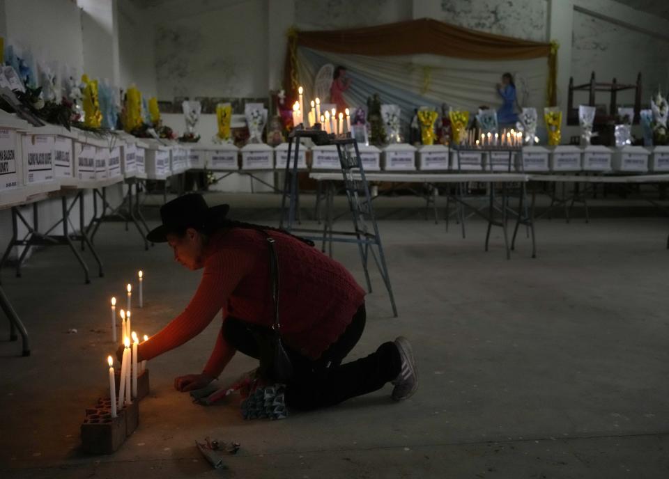 A woman lights candles in honor of people who were killed during the Maoist-inspired insurgency, after authorities returned to families the remains of victims, during a vigil in Accomarca, Peru, Wednesday, May 18, 2022. Peruvian authorities identified a group of 80 remains found in this community as men, women and children who were killed between 1980 and 2000 by both members of the Shining Path militant group and army soldiers. (AP Photo/Martin Mejia)