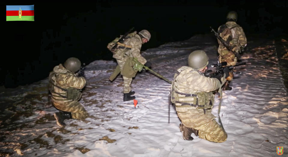 This photo taken from a video released by Azerbaijan's Defense Ministry on Wednesday, Nov. 25, 2020, shows an Azerbaijan's army soldiers and a de-miner during mine clearance in Kalbajar region of Azerbaijan. The Kalbajar district bordering Armenia, which houses one of the two roads linking Nagorno-Karabakh and the neighbouring country and has strategic significance for Armenians and Azeris, is due to be handed over to Azerbaijan according to a Russia-brokered cease-fire agreement between two countries in the long-running conflict over the separatist territory. (Azerbaijan's Defense Ministry via AP)