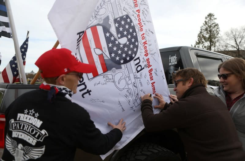 Militia members and pro-gun rights activists sign a flag while participating in the "Declaration of Restoration" rally in Washington, D.C.