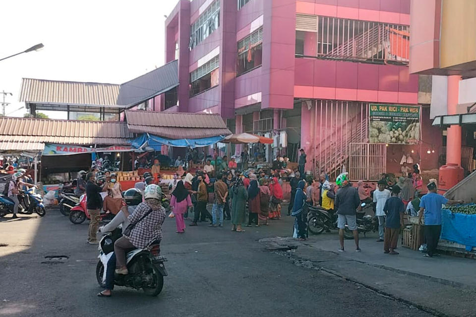 People wait outside after evacuating a market following an earthquake in Pekanbaru, Indonesia, Friday, Feb. 25, 2022. A strong and shallow earthquake hit off the coast of Indonesia's Sumatra island on Friday, panicking people in Sumatra island and neighboring Malaysia and Singapore. (AP Photo/Panji Rahmat)