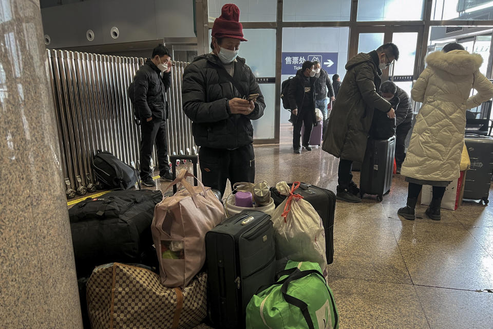 Travellers wearing face masks with their luggage arrive at the West Railway Station in Beijing, Friday, Jan. 6, 2023. China is seeking to minimize the possibility of a major new COVID-19 outbreak during this month's Lunar New Year travel rush following the end of most pandemic containment measures. (AP Photo/Wayne Zhang)