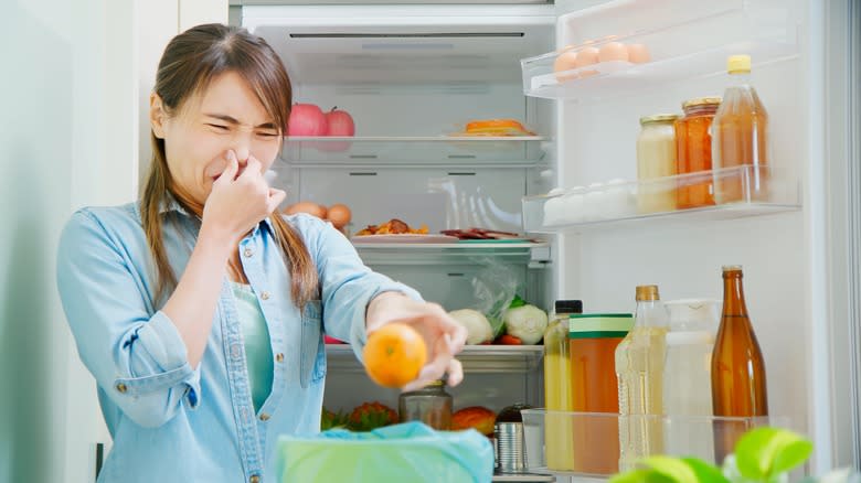 Person pulling spoiled food from fridge