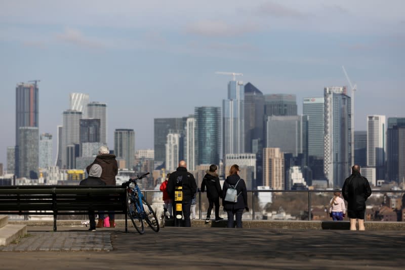 FILE PHOTO: People look out onto the Canary Wharf district as they walk through Greenwich Park in London