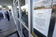 A sign warns that firearms are prohibited at Mary Mart, a marijuana store, Tuesday, April 19, 2022, in Tacoma, Wash., as armed security guard Austin MacMath stands watch outside at left. A surge in robberies at licensed cannabis shops in Washington state is helping fuel a renewed push for federal banking reforms that would make the cash-dependent stores a less appealing target. (AP Photo/Ted S. Warren)