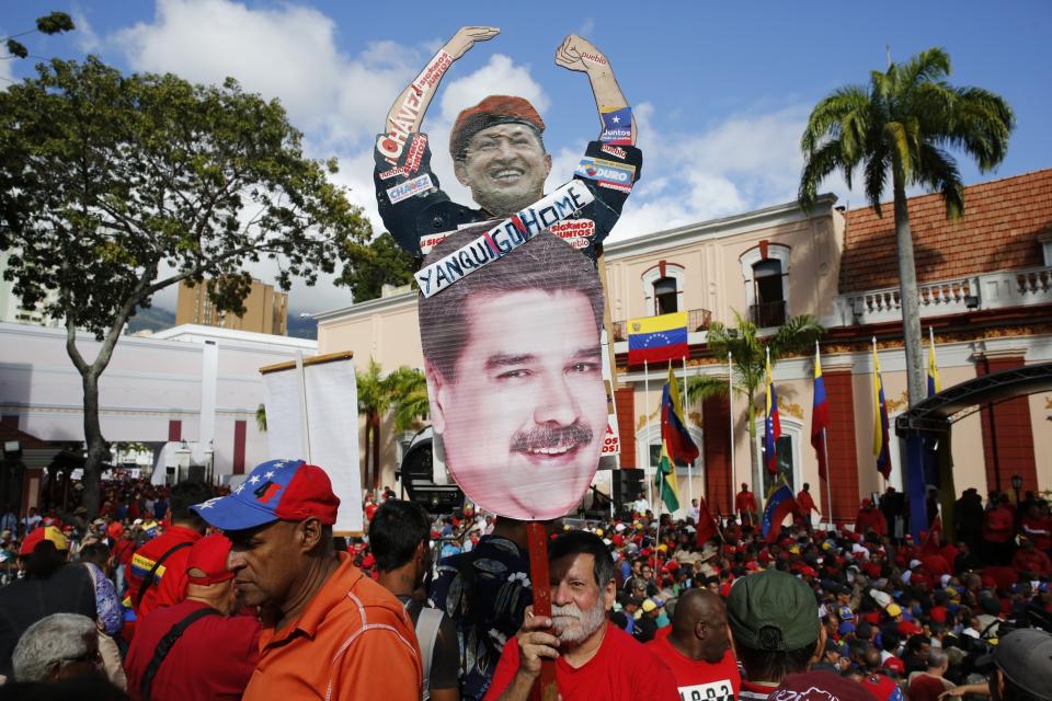 FILE - In this Jan. 23, 2019 file photo, a supporter of Venezuela's President Nicolas Maduro holds a homemade poster featuring images of Venezuela's late President Hugo Chaves and Maduro, with the message: "Yankee Go Home", during a rally outside the Miraflores presidential palace, in Caracas, Venezuela. Chavez was elected in 1998 with the overwhelming support of Venezuela’s middle class. But support for his hand-picked successor, Maduro, has plummeted amid galloping hyperinflation and widespread shortages. (AP Photo/Ariana Cubillos, File)