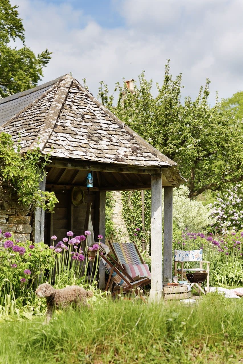 deckchairs beneath tiled gazebo, summerhouse in restful garden setting, pink allium flowers, rustic style, relaxation, hideaway