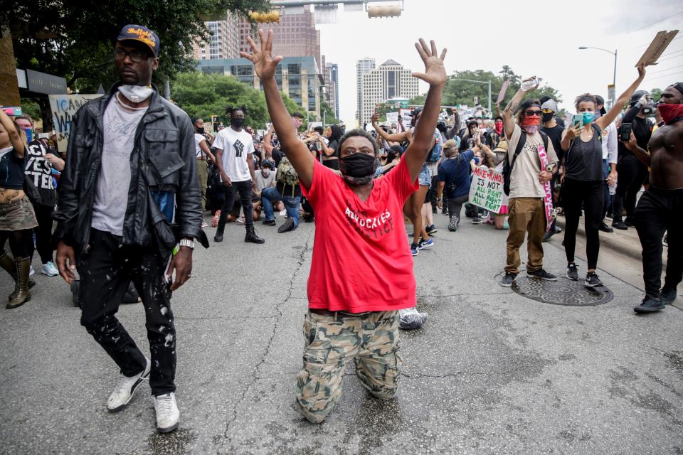 A man falls to his knees as protesters make their way down Cesar Chavez Street decrying the deaths of George Floyd in Minneapolis and Michael Ramos in Austin on May 31, 2020.