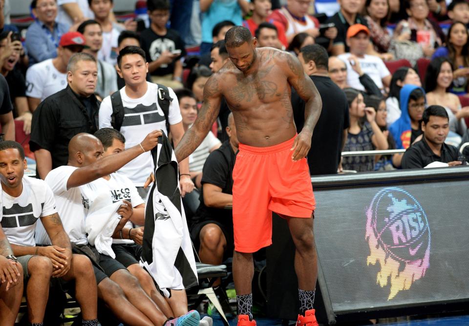 US NBA superstar LeBron James changes jersey as he prepares for an exhibition game as part of a clinic session in Manila on August 20, 2015. James is here to conduct basketball clinic to select talented baskeball players from disadvantaged families.    AFP PHOTO / TED ALJIBE        (Photo credit should read TED ALJIBE/AFP/Getty Images)