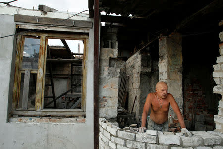 A local resident rebuilds his destroyed house near the airport in Donetsk, Ukraine, September 13, 2017. REUTERS/Alexander Ermochenko