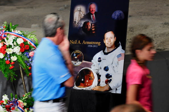 Tourists pass a poster and flowers in honor of former NASA astronaut Neil Armstrong at the Apollo/Saturn V Center, August 31, 2012 in Cape Canaveral, Florida. Armstrong, the first man to walk on the moon, died from complications from heart surgery at the age of 82. (Photo by Roberto Gonzalez/Getty Images)